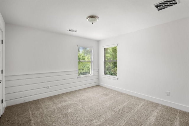 carpeted empty room featuring visible vents and baseboards