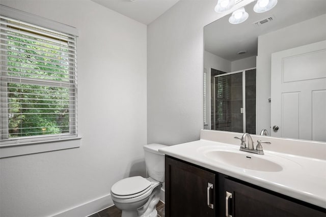 bathroom with visible vents, vanity, toilet, baseboards, and a stall shower