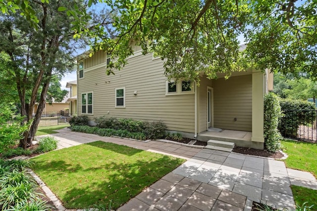 rear view of property featuring a lawn and fence