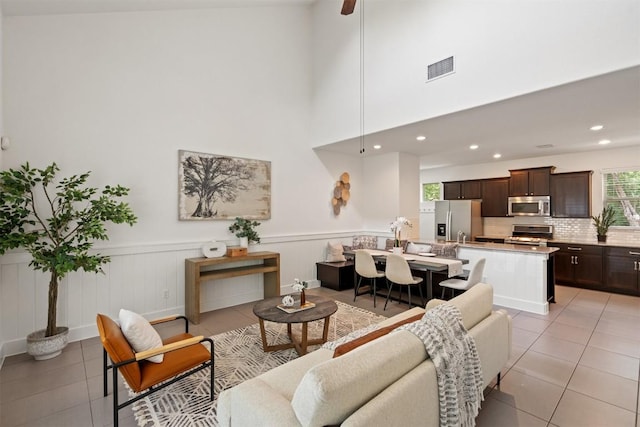 living area with light tile patterned floors, a wainscoted wall, recessed lighting, and visible vents