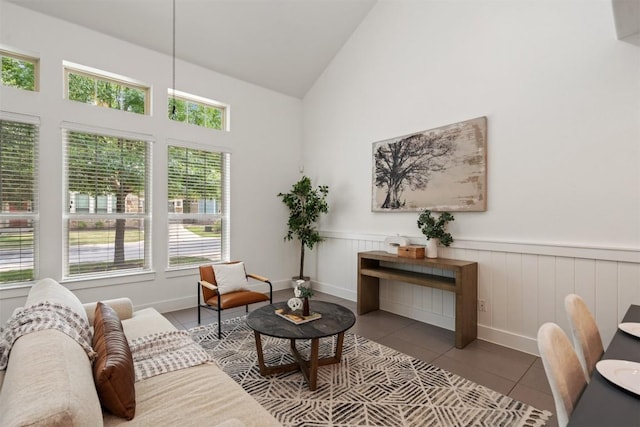 sitting room featuring tile patterned floors, wainscoting, and high vaulted ceiling