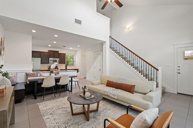 living area featuring visible vents, a towering ceiling, light tile patterned floors, and stairway