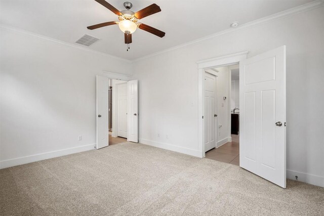 unfurnished bedroom featuring crown molding, visible vents, baseboards, ceiling fan, and light colored carpet