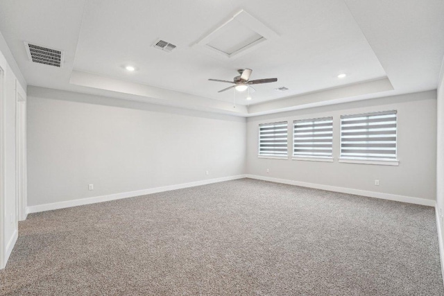 carpeted spare room with visible vents, baseboards, and a tray ceiling