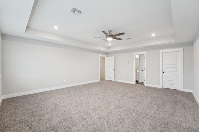 interior space featuring a tray ceiling, carpet, visible vents, and baseboards