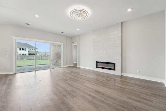 unfurnished living room with visible vents, baseboards, wood finished floors, and a large fireplace