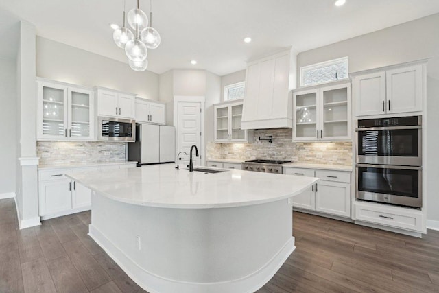 kitchen with white cabinets, an island with sink, stainless steel appliances, a sink, and tasteful backsplash