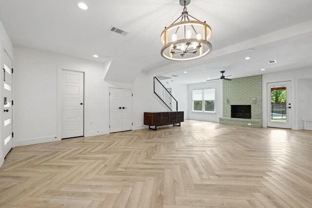 unfurnished living room with a fireplace, a healthy amount of sunlight, visible vents, and ceiling fan with notable chandelier