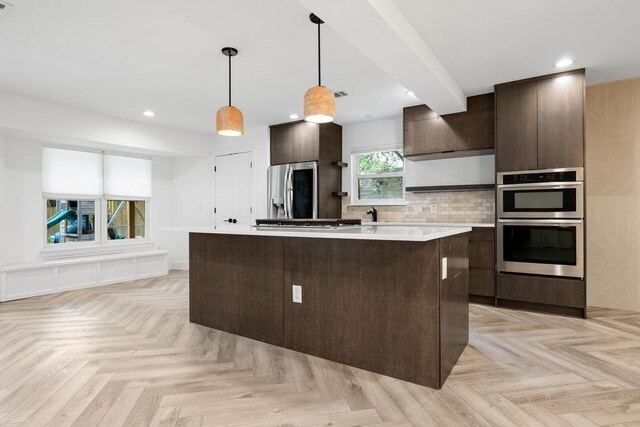 kitchen featuring dark brown cabinetry, stainless steel appliances, light countertops, a kitchen island, and recessed lighting