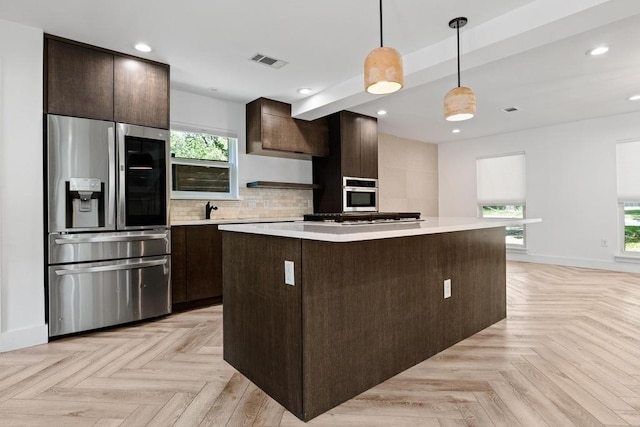 6905 Drexel Dr, Austin, TX 78723 - kitchen with stainless steel appliances, a center island, dark brown cabinetry, light countertops, and recessed lighting