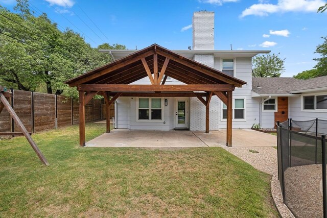 back of house featuring a yard, a patio, a fenced backyard, and a chimney