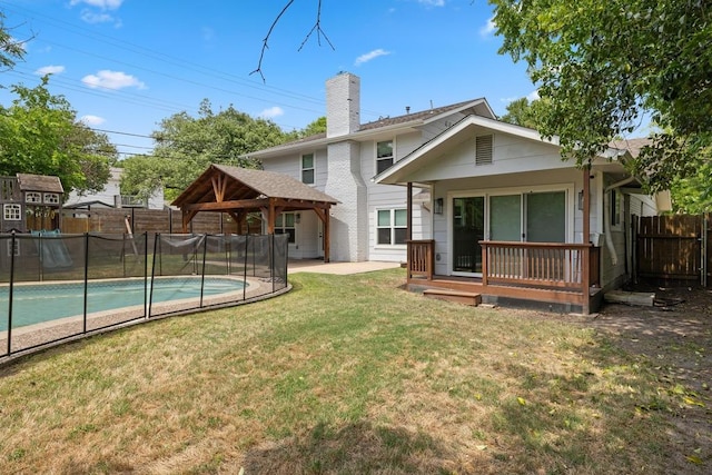 back of property featuring a gazebo, a chimney, a lawn, fence, and a fenced in pool