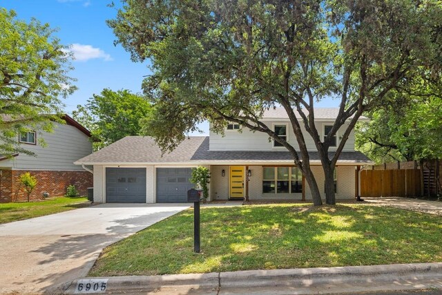 view of front of house with a front lawn, driveway, fence, brick siding, and an attached garage