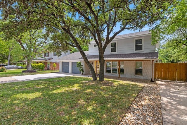 traditional-style home with fence, concrete driveway, brick siding, a front yard, and a garage