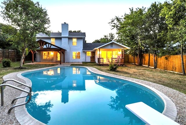 view of swimming pool with a fenced backyard, a diving board, a yard, a fenced in pool, and a wooden deck