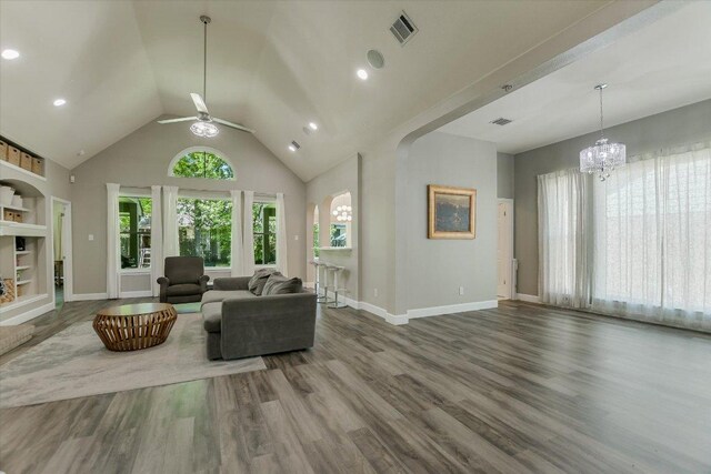 living room featuring baseboards, wood finished floors, visible vents, and ceiling fan with notable chandelier
