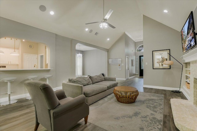 living area with wood finished floors, arched walkways, baseboards, high vaulted ceiling, and ceiling fan
