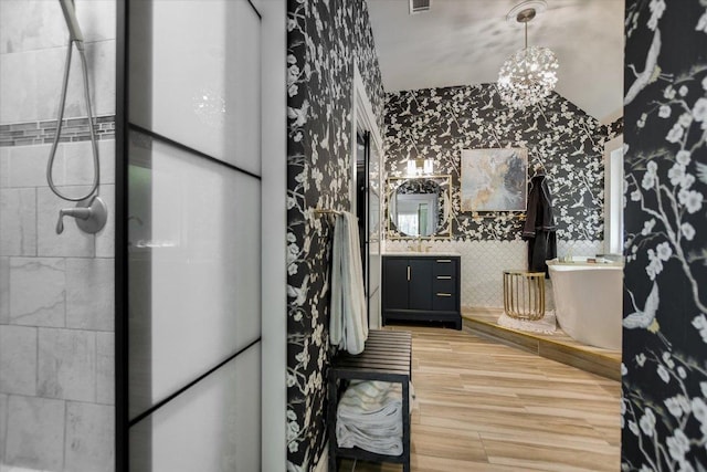 full bath featuring wallpapered walls, wood finished floors, vanity, and a stall shower