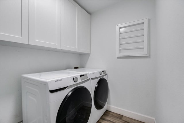 laundry area featuring washing machine and dryer, wood finished floors, baseboards, and cabinet space