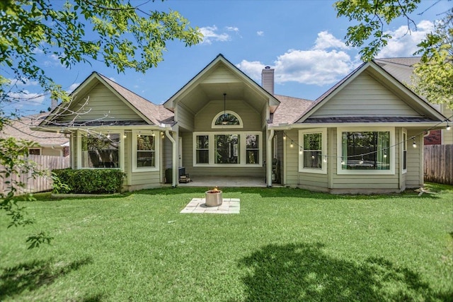 back of house featuring a chimney, fence, a patio area, a lawn, and a shingled roof