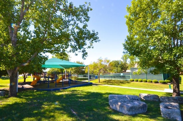view of property's community featuring a lawn, fence, and playground community
