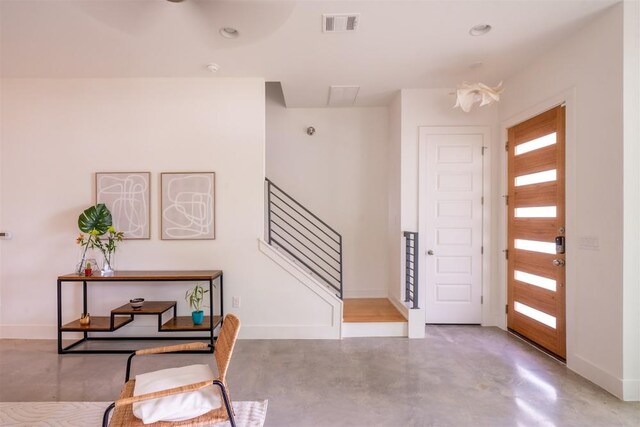 entryway featuring baseboards, visible vents, finished concrete floors, and stairs