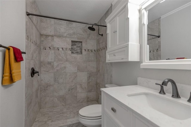 full bath with a tile shower, toilet, and vanity
