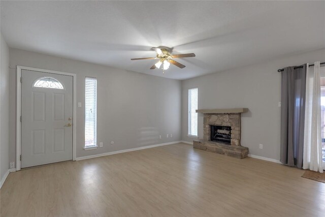 unfurnished living room with a ceiling fan, a fireplace, a wealth of natural light, and light wood-style flooring
