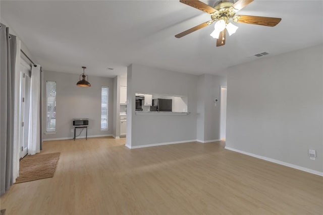 unfurnished living room with light wood-type flooring, baseboards, visible vents, and ceiling fan