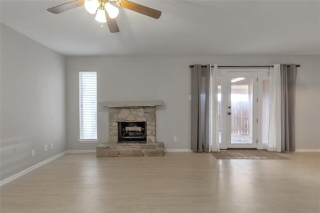 unfurnished living room featuring wood finished floors, a healthy amount of sunlight, and baseboards