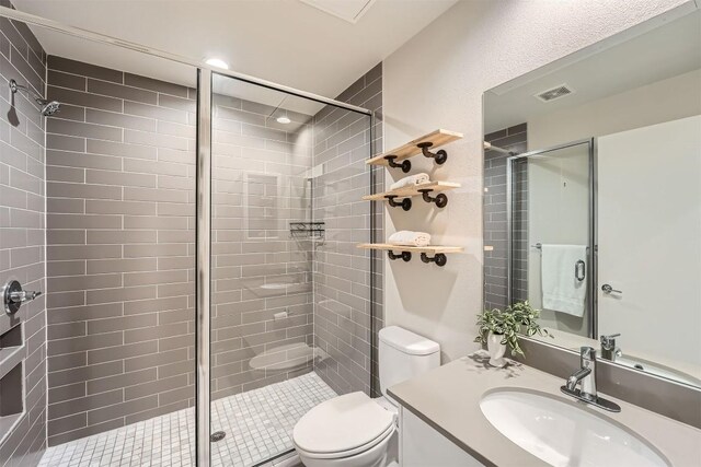 bathroom with a stall shower, visible vents, vanity, and toilet
