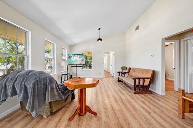 living area featuring light wood finished floors, baseboards, lofted ceiling, and visible vents