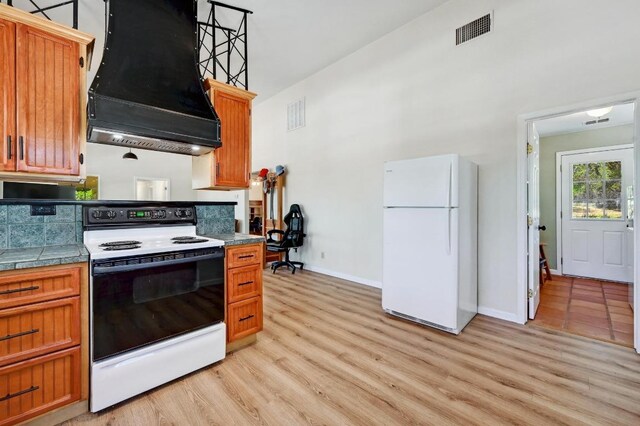 kitchen with visible vents, light wood finished floors, exhaust hood, and white appliances