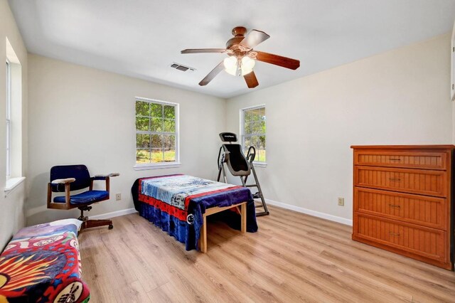 bedroom with light wood-type flooring, visible vents, a ceiling fan, and baseboards