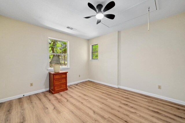 unfurnished room featuring attic access, ceiling fan, light wood finished floors, baseboards, and visible vents