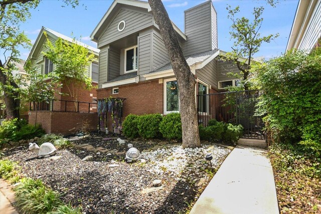 view of property exterior featuring a chimney, fence, and brick siding