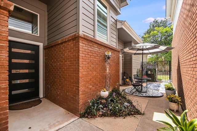 view of side of home featuring brick siding, a patio, and a gate