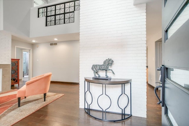 interior space featuring baseboards, visible vents, a high ceiling, and dark wood-style floors