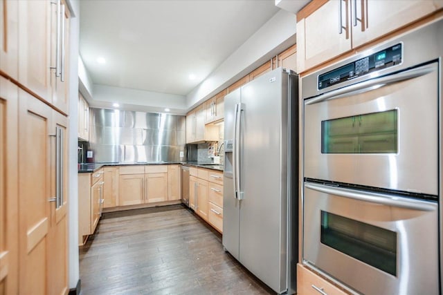 kitchen with recessed lighting, backsplash, wood finished floors, light brown cabinets, and appliances with stainless steel finishes
