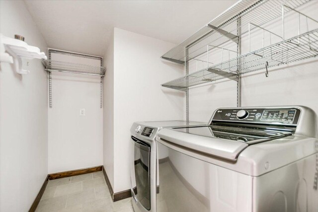 washroom featuring baseboards, washer and clothes dryer, and laundry area