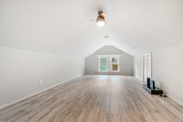 bonus room with lofted ceiling, light wood finished floors, baseboards, and ceiling fan