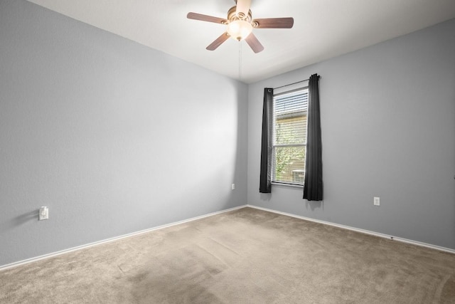 carpeted spare room with a ceiling fan and baseboards