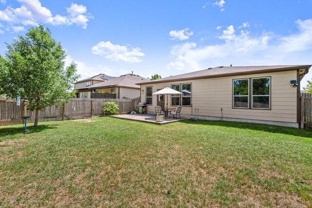 rear view of property featuring a fenced backyard, a yard, and a patio