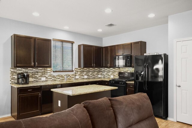 kitchen featuring tasteful backsplash, dark brown cabinets, black appliances, open floor plan, and visible vents