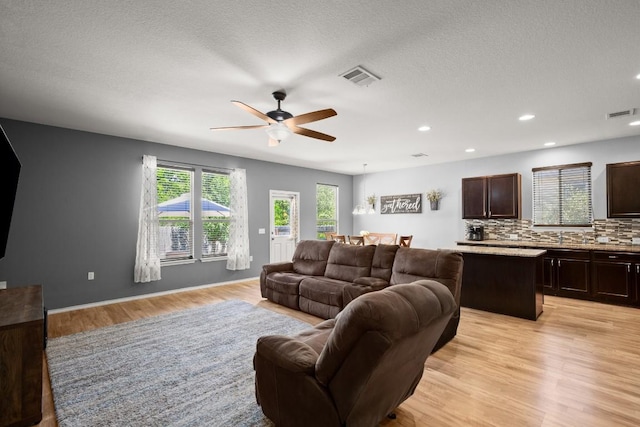 15204 Guffey Dr, Austin, TX 78725 - living area featuring healthy amount of natural light, light wood finished floors, a ceiling fan, recessed lighting, and a textured ceiling