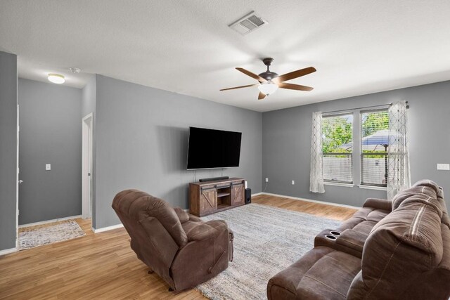 living room with ceiling fan, baseboards, light wood-style floors, and visible vents