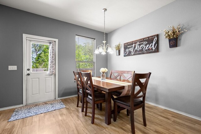 dining room with light wood-type flooring, baseboards, and a notable chandelier