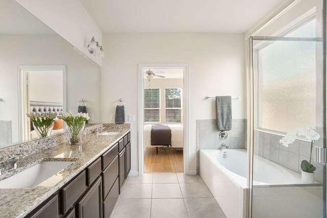 ensuite bathroom featuring tile patterned floors, a garden tub, a sink, and double vanity