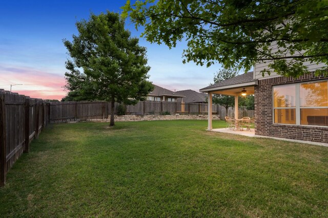 yard at dusk with a fenced backyard and a patio