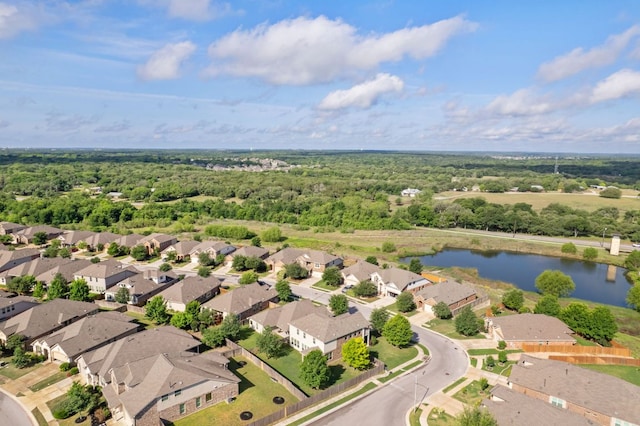 drone / aerial view with a wooded view, a residential view, and a water view